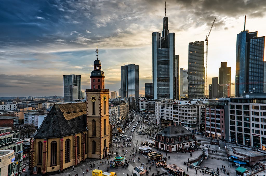 A stunning cityscape of Frankfurt featuring skyscrapers and a historic church at sunset.