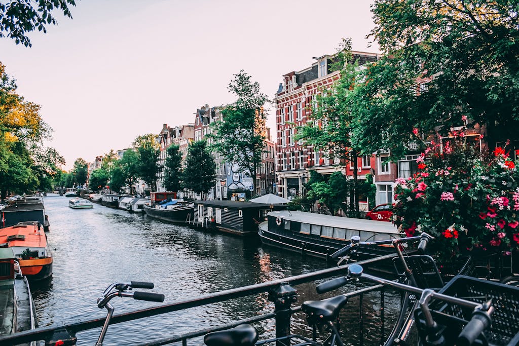 Charming view of Amsterdam canal lined with historic buildings and bicycles at sunset.