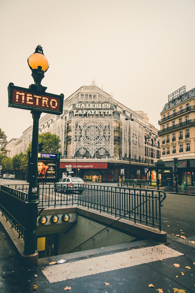 Discover the iconic Galeries Lafayette facade in Paris with nearby metro signs on an overcast day.