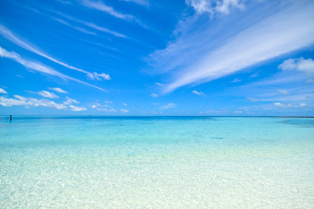 Experience the tranquil turquoise waters and clear sky at Laamu Atoll, Maldives. Perfect for a relaxing getaway.