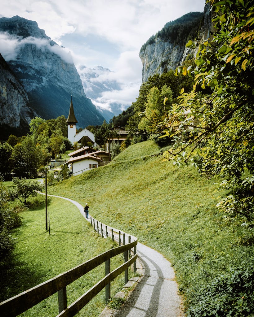 Idyllic summer scene with mountain backdrop and pathway in a lush valley.