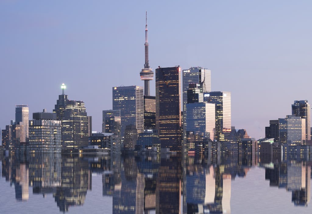 Stunning reflection of Toronto skyline with CN Tower at sunset, showcasing modern architectural marvels in Canada.